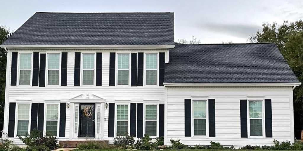Two-story white house featuring black shutters and a new asphalt shingle roof