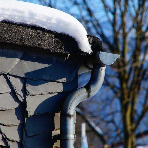 Snow-covered gutter on a Twin Cities home — without guards, debris freezes and traps water